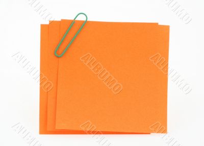 three orange notes with green paperclip