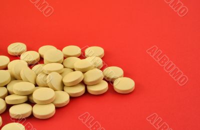 handful of yellow tablets on red