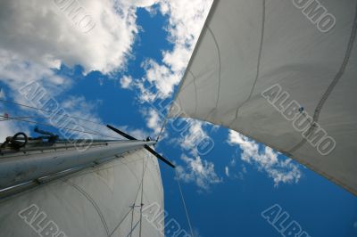 Mast with sails on sky background