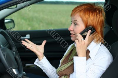 Red-haired woman with mobile-phone in a car Red-haired woman with mobile-phone in a car