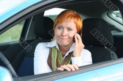 Red-haired woman with mobile-phone in a car