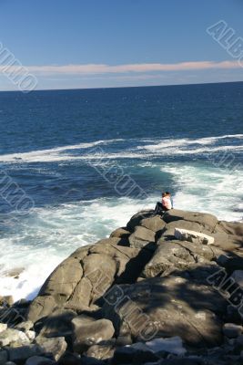 Visitor watching the tide from rocky perch