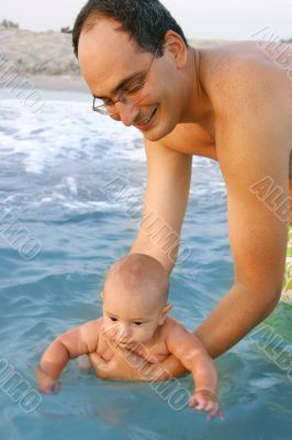 father teachning his baby son to swim