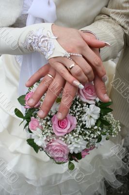 Female and male newlyweds hands with bouquete