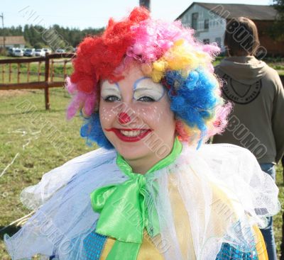 Expressive clown in colored wig upon blue sky