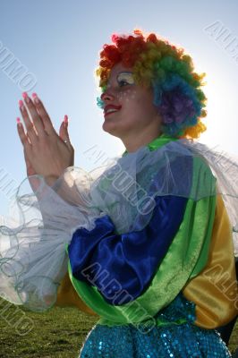 Expressive clown in colored wig upon blue sky