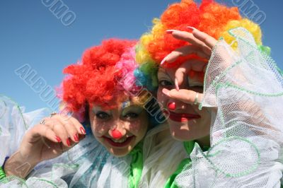 Two bizzare clowns in colored wigs upon blue sky Two bizzare clowns in colored wigs upon blue sky