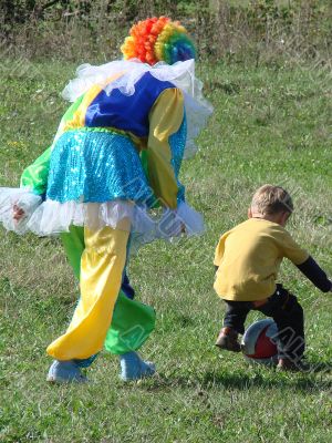 Clown in colored wig plays with child