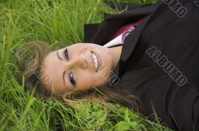 The beautiful girl sits on a green grass