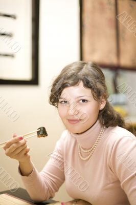 Girl eating sushi in Japanese restaurant