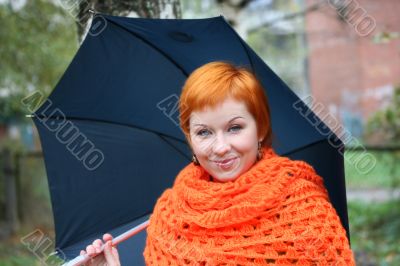 young red-haired woman in red scarf with umbrella