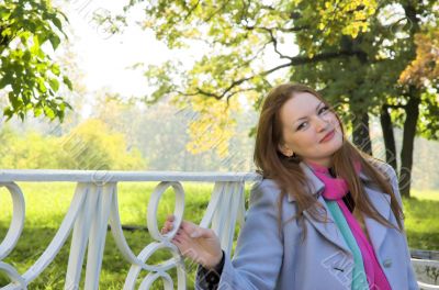The girl sits on a bench in autumn park