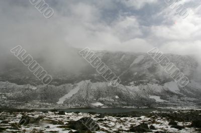 snow mountain in fog with cold lake