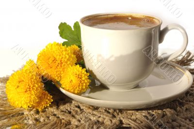 A cup of coffee and  yellow flower