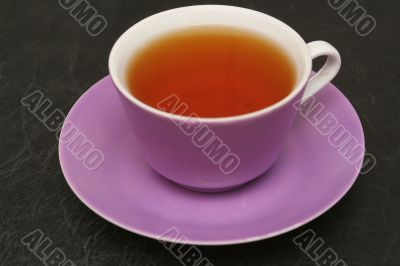 Lilac cup with tea on a black background