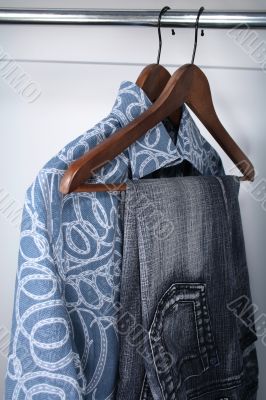 Blue jeans and shirts on wooden hangers