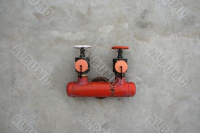 Red iron valve on a cement wall