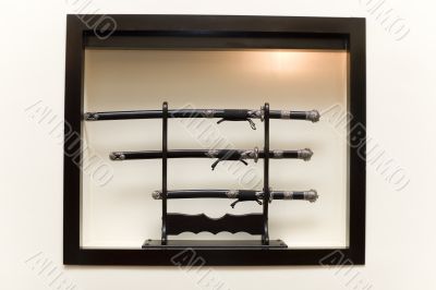 Three japanese swords on pedestal in the illuminated niche Three japanese swords on pedestal in the illuminated niche