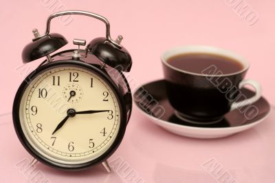 The black alarm clock and black cup from coffee
