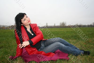 black head woman is sitting on a Plaid in park grass