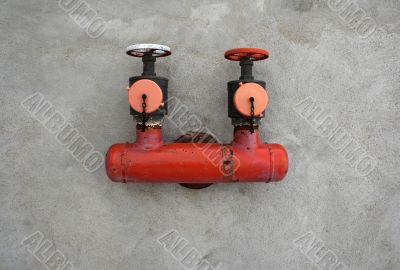 Red iron valve on a concrete wall