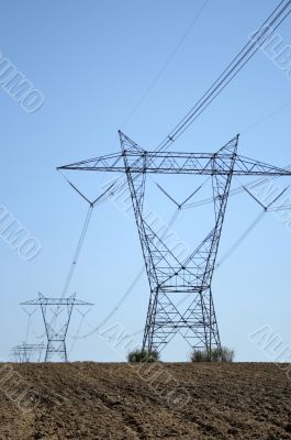 Electricity pylons in ploughed land