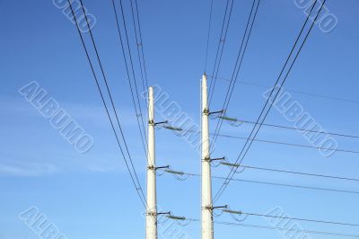 Two white electricity pylons and stretching wires