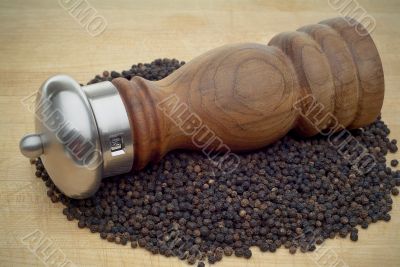 Pepper Mill in pepper on wooden cutting board