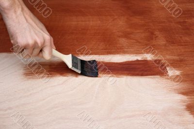Man`s hand painting a wooden surface