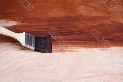 Paint brush painting a wooden surface