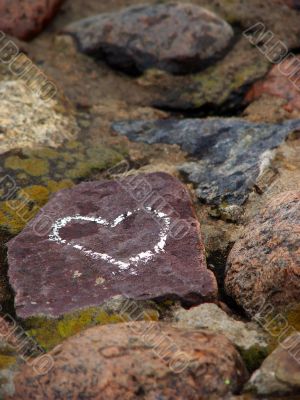 Heart sign drawn on a stone of a river shore.