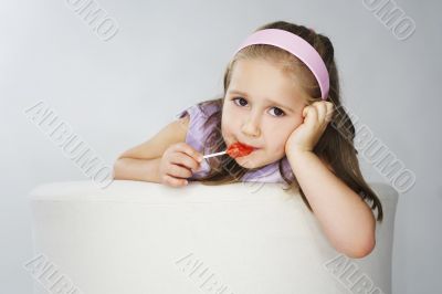 Nice young girl in pink on light background with lollipop