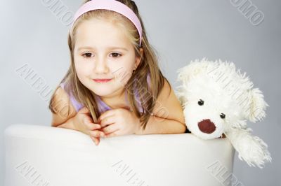 Nice young girl in pink on light background with teddy bear