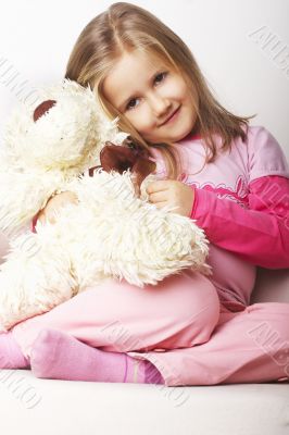 Nice young girl in pink on light background with teddy bear