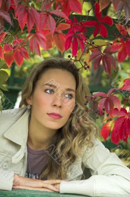 The beautiful blonde in red leaves of grapes