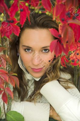 The beautiful blonde in red leaves of grapes