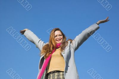 The happy girl on a background of the blue sky