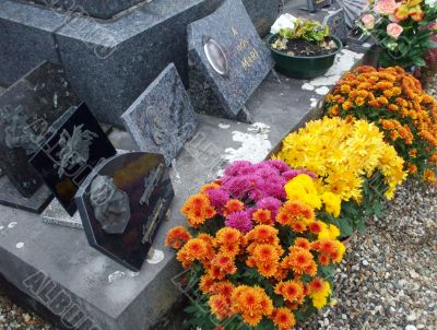 In a cemetery, a gravestone decorated with flowers in autumn