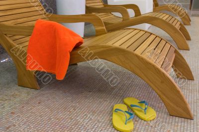 sunbed with orange towel with sandals