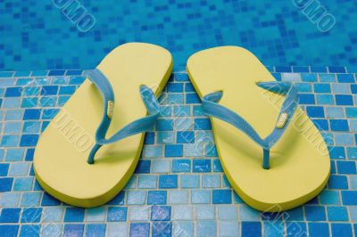 yellow sandals on the blue coast of pool