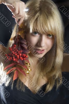 young blonde girl holds a branch of a mountain ash