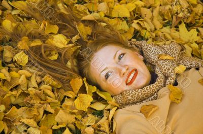 The red-haired woman lays in yellow leaves The red-haired woman lays in yellow leaves