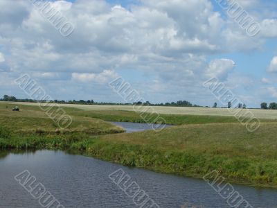 wide summer field with river uder cloudy blue sky wide summer field with river uder cloudy blue sky