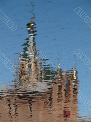 Church Cupola with Cross reflected in wavy water