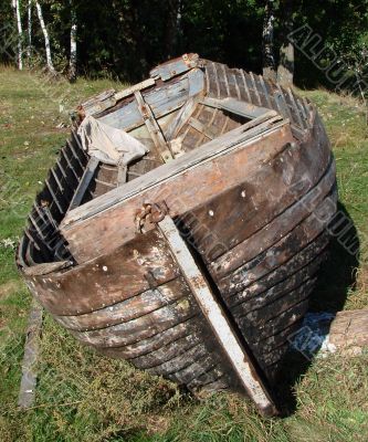 ruined vintage wooden boat on riverside