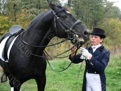 equestrian spotswoman holds black stallion