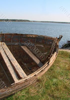 ruined vintage wooden boat on riverside