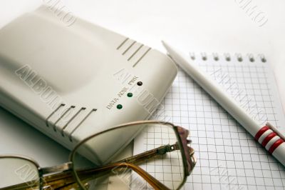 modem, notebook, pen and glasses