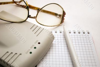 modem, notebook, pen and glasses