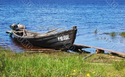 Old wooden fishing motor boat by the lake bank